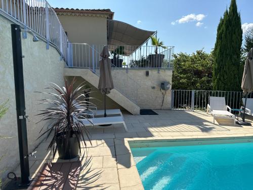 a swimming pool with an umbrella next to a house at Bastide Saint-Thomé in Saint-Thomé