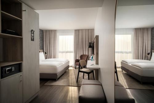 um quarto de hotel com duas camas e uma secretária em Arthotel ANA Amber em Rostock