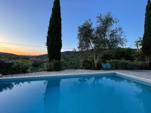 une piscine bleue avec un coucher de soleil en arrière-plan dans l'établissement Gîtes du Clos Cèze Art, à Saint-André-de-Roquepertuis