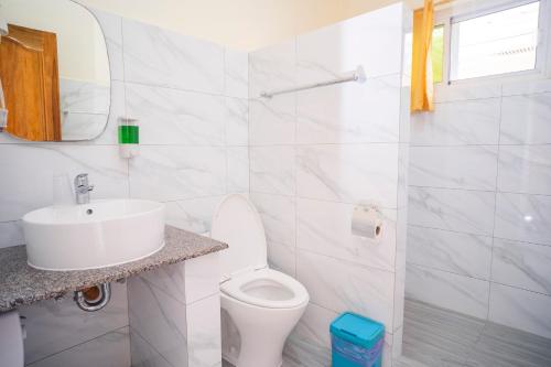 a white bathroom with a toilet and a sink at Alona Austria Resort in Panglao