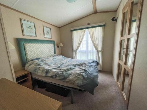 a small bedroom with a bed and a window at Lovely 6 Berth Caravan With Decking, Wifi And Onsite Beach Access Ref 68004cl in Lowestoft