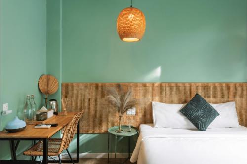 a bedroom with a bed and a table and a desk at Leaf Hotel Phu Quoc in Phu Quoc