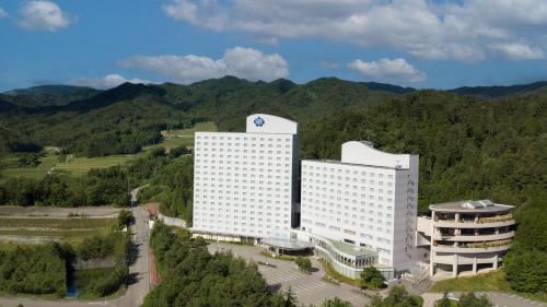 una vista aérea de un edificio con montañas en el fondo en Hotel Associa Takayama Resort, en Takayama