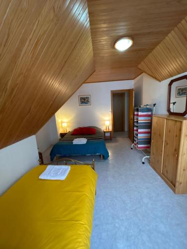 a bedroom with two beds and a wooden ceiling at la vallee in Plogoff