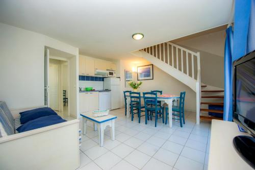 un salon avec une cuisine et une table et des chaises dans l'établissement Résidence Goélia La Palmeraie, à Saint-Georges-dʼOléron