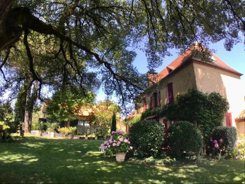 a house with flowers in front of a yard at Les Temps des Sources in Veyrines-de-Domme