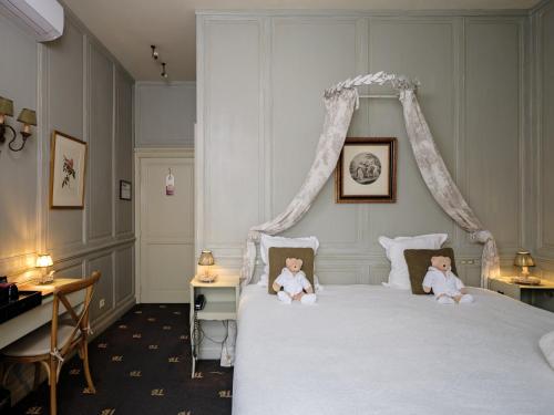 a bedroom with a bed with two dolls sitting on it at Hotel Ter Brughe by CW Hotel Collection in Bruges