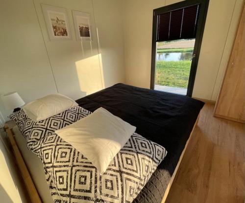 een slaapkamer met een bed met zwarte lakens en een raam bij Domki Nad Malowniczym Stawem / Raj Dla Wędkarzy / Mazury in Piecki