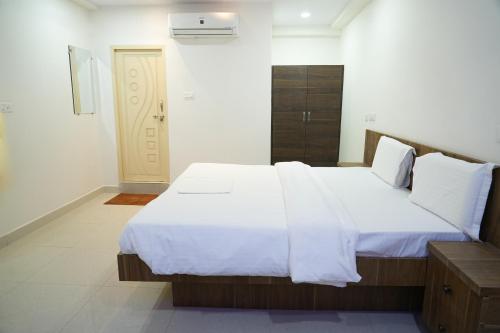 a bedroom with a large bed with white sheets at 5 STAR GRAND- PREMIUM in Shamshabad