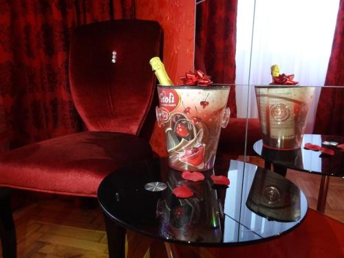 ein Tisch mit einem Stuhl und einer Flasche Champagner in der Unterkunft Amour Rouge Suite (Adults Only) in Galaţi