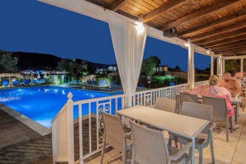 a couple sitting at a table on a deck overlooking a swimming pool at Grapevines Hotel in Alikanas