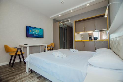 una camera con un grande letto bianco e una scrivania di Alliance Palace Aparthotel a Batumi
