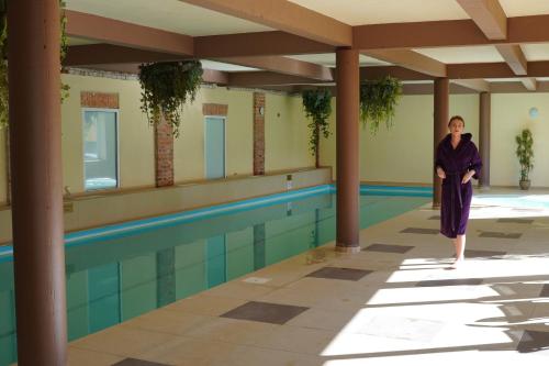 a woman in a robe standing next to a swimming pool at Romantic Boutique Hotel & Spa in Panevėžys