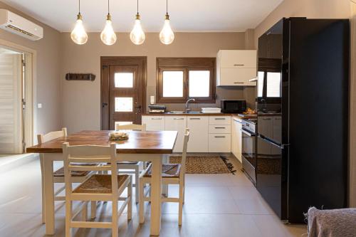 a kitchen with a wooden table and a black refrigerator at Irinis Apartments Karfas, Chios in Chios