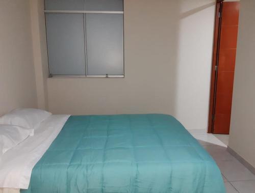 Un dormitorio con una cama con una manta azul. en El Valle Lunahuaná, en Lunahuaná