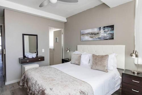 a bedroom with a large white bed and a mirror at 801 Infinity 2 Bedroom Beachfront Apartment in Cape Town