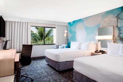 a hotel room with two beds and a desk at Courtyard by Marriott Fort Lauderdale Coral Springs in Coral Springs