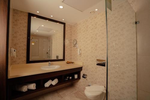 a bathroom with a sink and a mirror and a toilet at Carmel Hotel in Ramallah