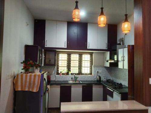 cocina con armarios blancos y nevera negra en Trekkers Villa en Wayanad