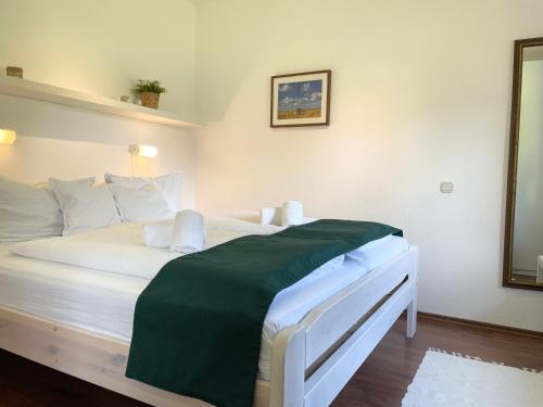 Un dormitorio con una cama blanca con una manta verde. en Haus Land & Meer FeWo14, en Cuxhaven