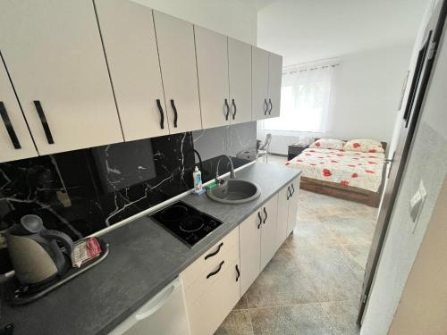 uma cozinha com armários brancos, um lavatório e uma cama em Willa Afrodyta em Krynica Morska