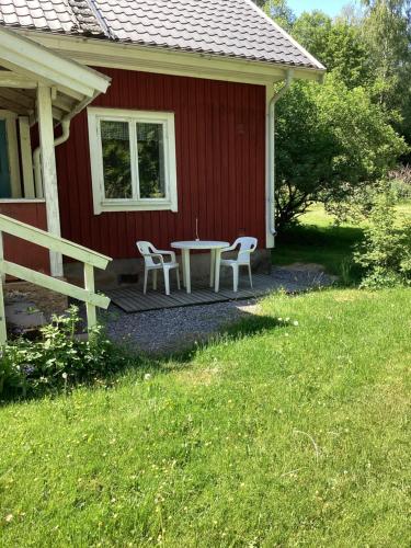 a table and two chairs on a porch of a red house at Parhus i Rönneshytta in Rönneshytta