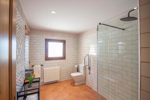 a bathroom with a toilet and a glass shower at Casa Rural Cal Martí in El Pla de Manlleu