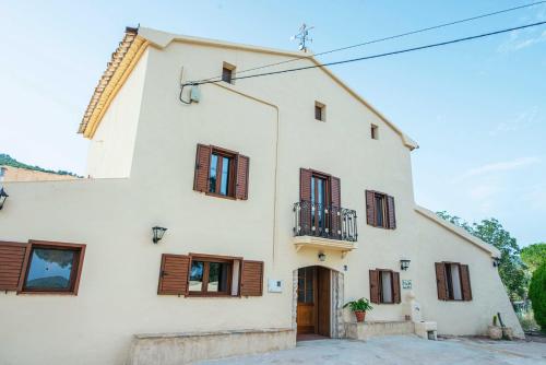 a large white house with wooden shutters at Casa Rural Cal Martí in El Pla de Manlleu