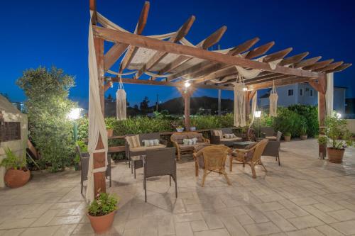 a patio with a wooden pergola and tables and chairs at Grapevines Hotel in Alikanas