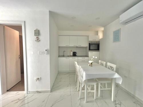 a kitchen and dining room with a white table and chairs at ZARA APARTMENTS in Koper