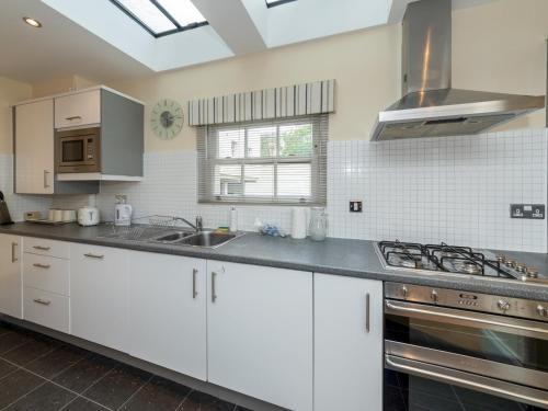 a kitchen with white cabinets and a sink and a stove at Pass the Keys Charming 3 BDR Home close to Reading Town Centre in Reading