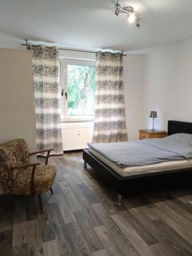 1 dormitorio con 1 cama, 1 silla y 1 ventana en Wohnung am Waldrand, en Melle