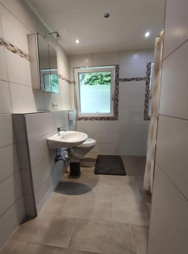 a white bathroom with a sink and a window at Wohnung am Waldrand in Melle