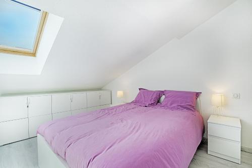 Dormitorio blanco con cama morada y ventana en L'évasion - Charmant appt pour 4, en La Bresse