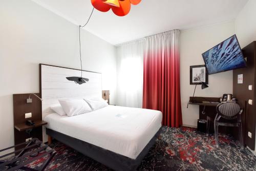 a hotel room with a bed and a desk and a bed at Hôtel Kyriad La Rochelle Centre Ville in La Rochelle