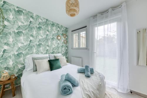 une chambre avec un lit blanc avec des serviettes dessus dans l'établissement Maison 4 chambres - 12 personnes - Parking Privé - Metro 7 - Rer B -, à La Courneuve