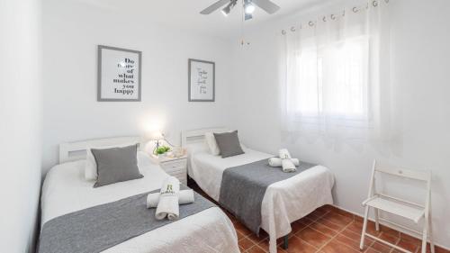 2 camas en una habitación con paredes blancas y ventana en Cortijo Las Vistas Cómpeta by Ruralidays en Cómpeta