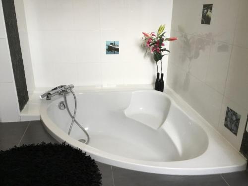 d'une baignoire blanche avec un vase et des fleurs. dans l'établissement Villa moderne piscine privée calme soleil près de Nîmes, à Clarensac