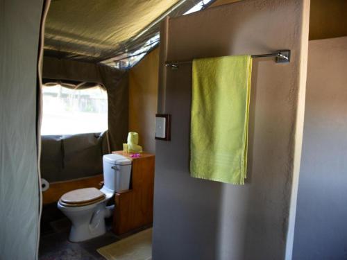 a bathroom with a toilet and a yellow shower curtain at Kayova River Lodge in Ndiyona