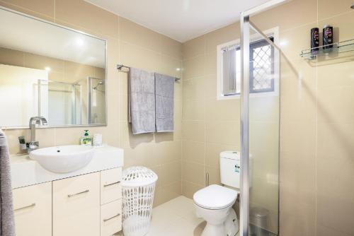 a bathroom with a toilet and a sink and a shower at Super Host! 2 bedrooms, Restaurants & Train in Brisbane