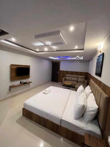 a bedroom with a bed and a couch and a television at Hotel Avenue Suites Near International Airport Bangalore in Bengaluru