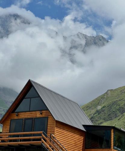 a log cabin with mountains in the background at Kazbegi Inn Cottages in Stepantsminda