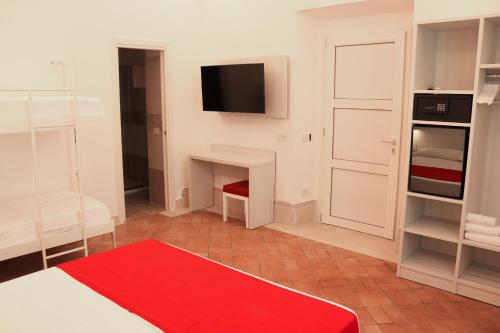 a room with a red rug and a tv on the wall at Primavilla Relais in Gaeta