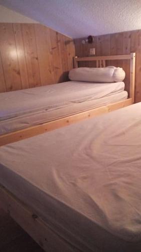 Cette chambre comprend 2 lits blancs dans un dortoir doté de murs en bois. dans l'établissement Logement dans chalet à la montagne, à Montferrier