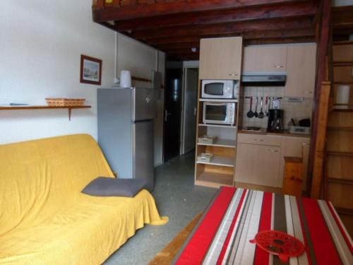 Cet appartement comprend une chambre avec un lit jaune et une cuisine. dans l'établissement Logement dans chalet à la montagne, à Montferrier