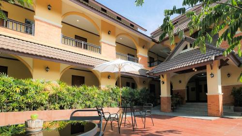 a courtyard of a building with chairs and an umbrella at Siam Avari Hotel, Chiang Rai in Chiang Rai