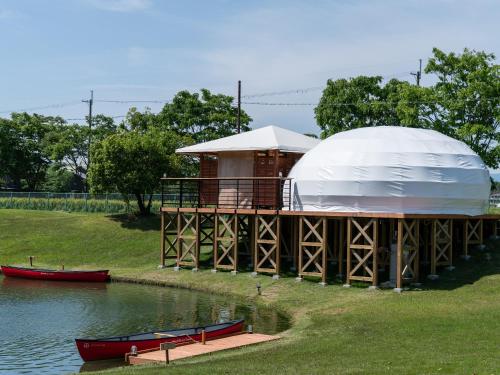 a luxury yurt with a boat on the water at GLAMP ELEMENT(グランエレメント） in Maibara