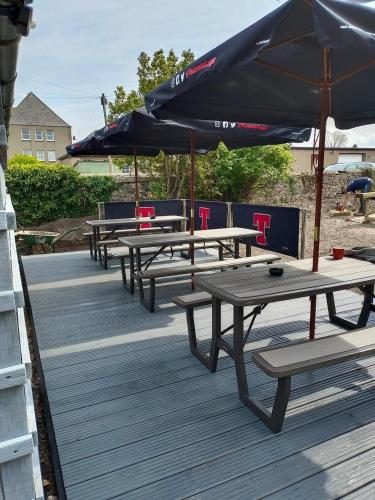 a row of picnic tables with an umbrella on a deck at The Brig & Barrel hotel in Buckie