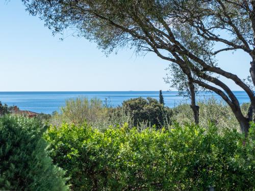 a view of the ocean from behind some trees at Casa Flaminia Villasimius in Villasimius