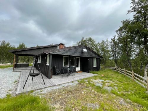 eine kleine schwarze Hütte mit einer Holzterrasse in der Unterkunft Sigurdhytta in Ål